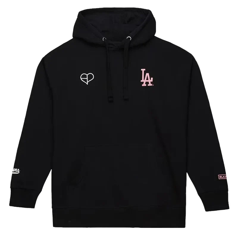 A black pullover hoodie with a white heart outline logo on the left chest and a pink 'LA' logo on the right chest, displayed on a light gray background.