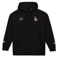 A black pullover hoodie with a white heart outline logo on the left chest and a pink 'LA' logo on the right chest, displayed on a light gray background.