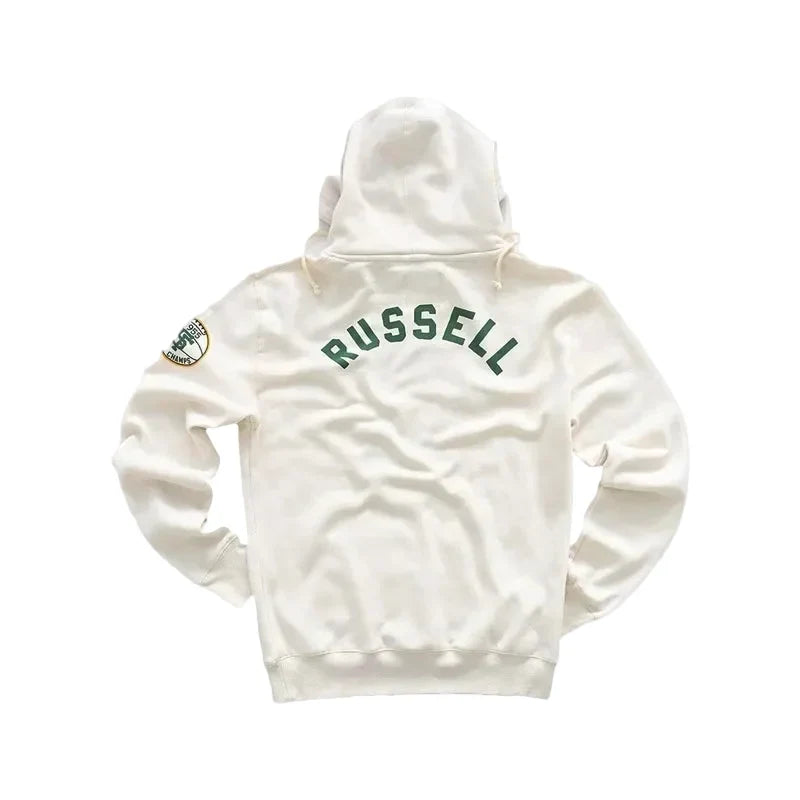 An off-white hooded sweatshirt shown from the back, featuring 'RUSSELL' printed in dark green arched block letters across the upper back and a small circular patch on the left sleeve, set against a solid light gray background.