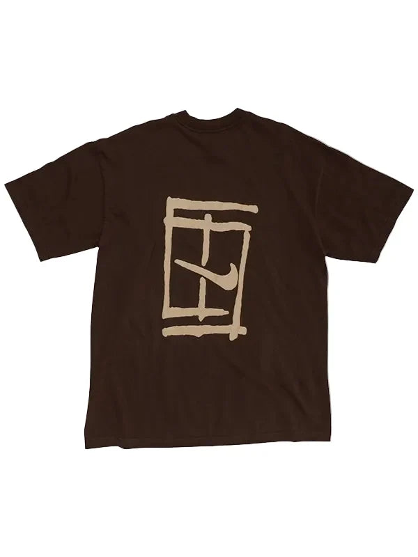 A dark brown short-sleeve t-shirt with a beige graphic print on the front, featuring a stylized window frame and a Nike swoosh, displayed against a light gray background.