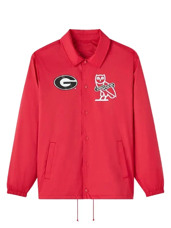 A red Coach jacket featuring the Georgia Bulldogs logo on the left chest and the iconic Coach owl logo on the right chest, displayed against a neutral gray background.