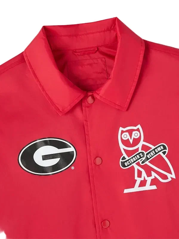 A close-up of a red button-front collared shirt jacket featuring a black-and-white Georgia 'G' logo on the left chest and a white owl graphic with 'October's Very Own' text on the right chest, shown against a light gray background.